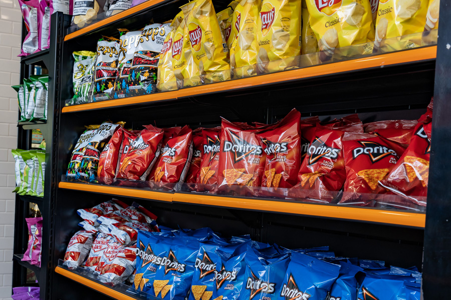 Doritos, Lays, and other chips line snack aisle.